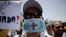Seorang dokter memakai masker saat unjuk rasa menuntut Presiden Venezuela Nicolas Maduro karena memburuknya ekonomi dan kondisi kemanusiaan di Caracas, Venezuela, (22/5). Sedikitnya 46 orang telah meninggal dunia. (AP Photo/Ariana Cubillos)