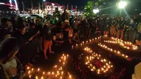 suporter Persebaya Surabaya, Bonek, menggelar doa bersama dan menyalakan lilin untuk korban Tragedi Kanjuruhan di Monumen Gubernur Suryo, Taman Apsari, Surabaya, Minggu (2/10/2022) malam. (Bola.com/Istimewa)