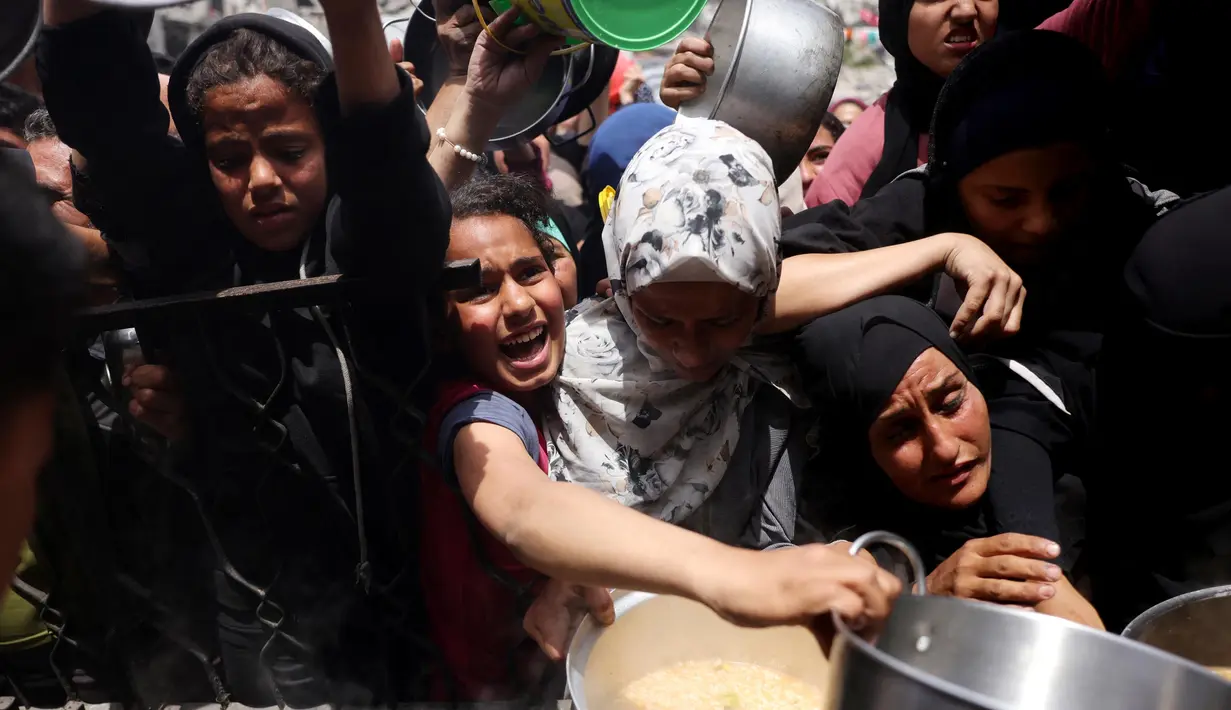 Warga Palestina berjuang untuk mendapatkan jatah makanan mereka di luar pusat distribusi di Beit Lahia, Jalur Gaza Utara pada 15 Mei 2025. (BASHAR TALEB/AFP)