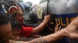 Demonstran terlibat saling dorong dengan polisi anti huru hara saat menggelar aksi pada ulang tahun Ferdinand Marcos ke-100 di Manila (11/9). Para demonstran menyerukan keadilan bagi korban darurat militer pada masa Ferdinand Marcos.(AFP Photo/Ted Aljibe)