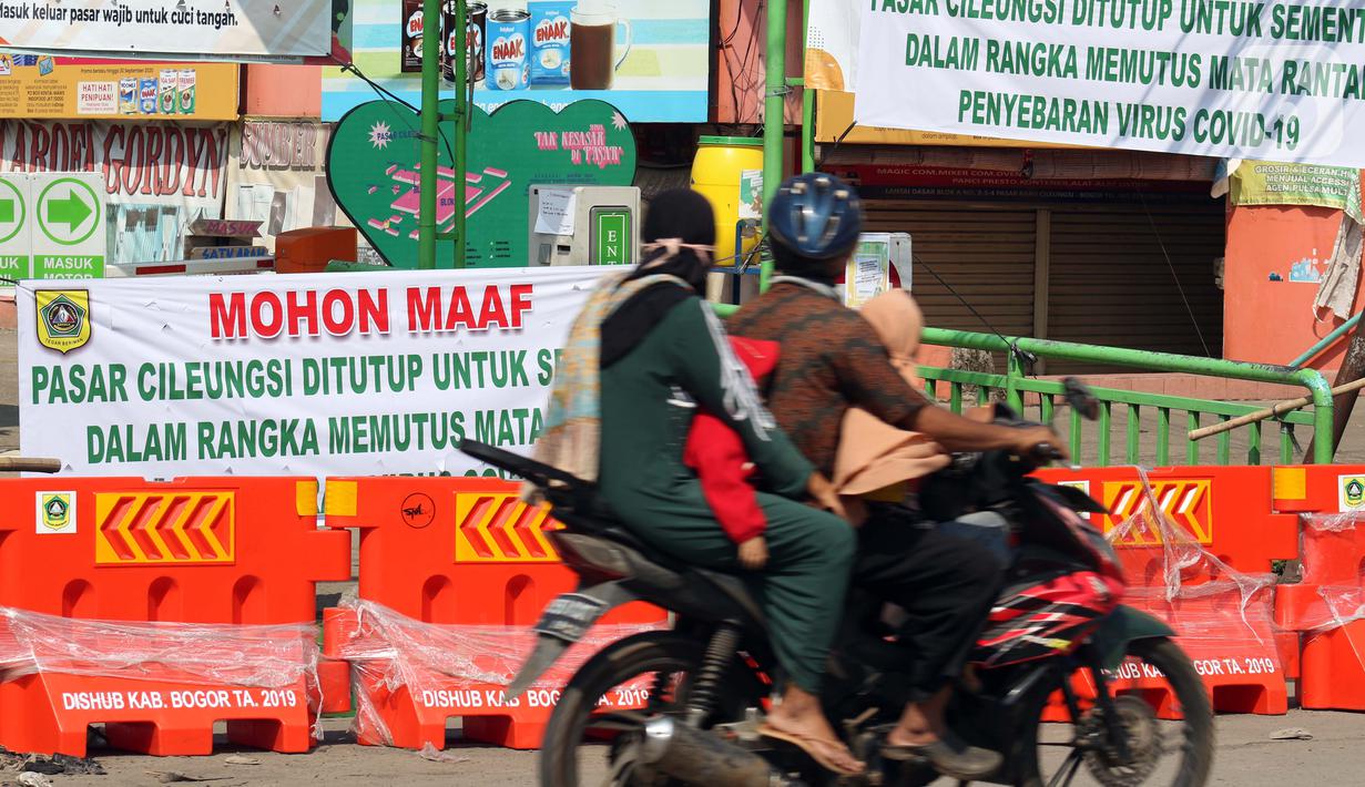 Warga melintasi pintu masuk kawasan Pasar Cileungsi yang dipenuhi spanduk penutupan, Kabupaten Bogor, Selasa (2/6/2020). Penutupan sementara kegiatan jual beli di Pasar Cileungsi terkait adanya tujuh pedagang yang positif terinfeksi virus COVID-19. (Liputan6.com/Helmi Fithriansyah)