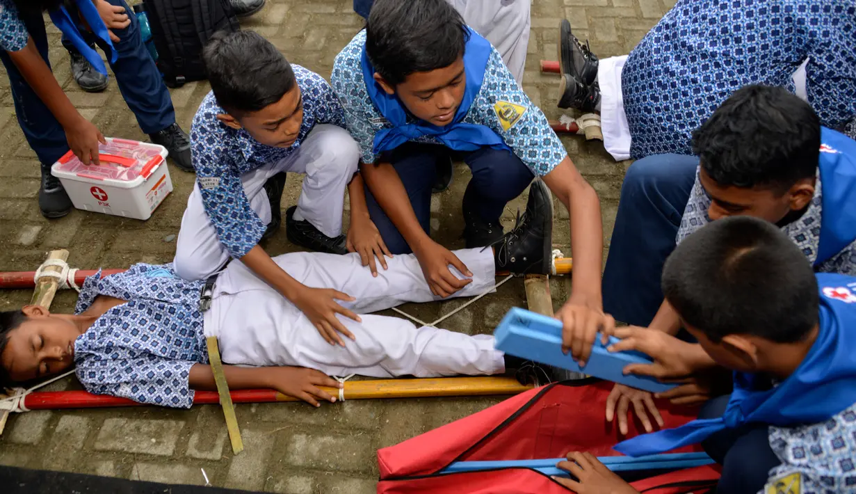 Sejumlah siswa memberikan pertolongan pertama saat simulasi bencana gempa dan tsunami di sebuah sekolah di Banda Aceh, Aceh, Rabu (9/10/2019). Simulasi dilakukan karena Aceh merupakan daerah rawan kedua bencana tersebut dan turut merusak bangunan sekolah. (Photo by CHAIDEER MAHYUDDIN / AFP)