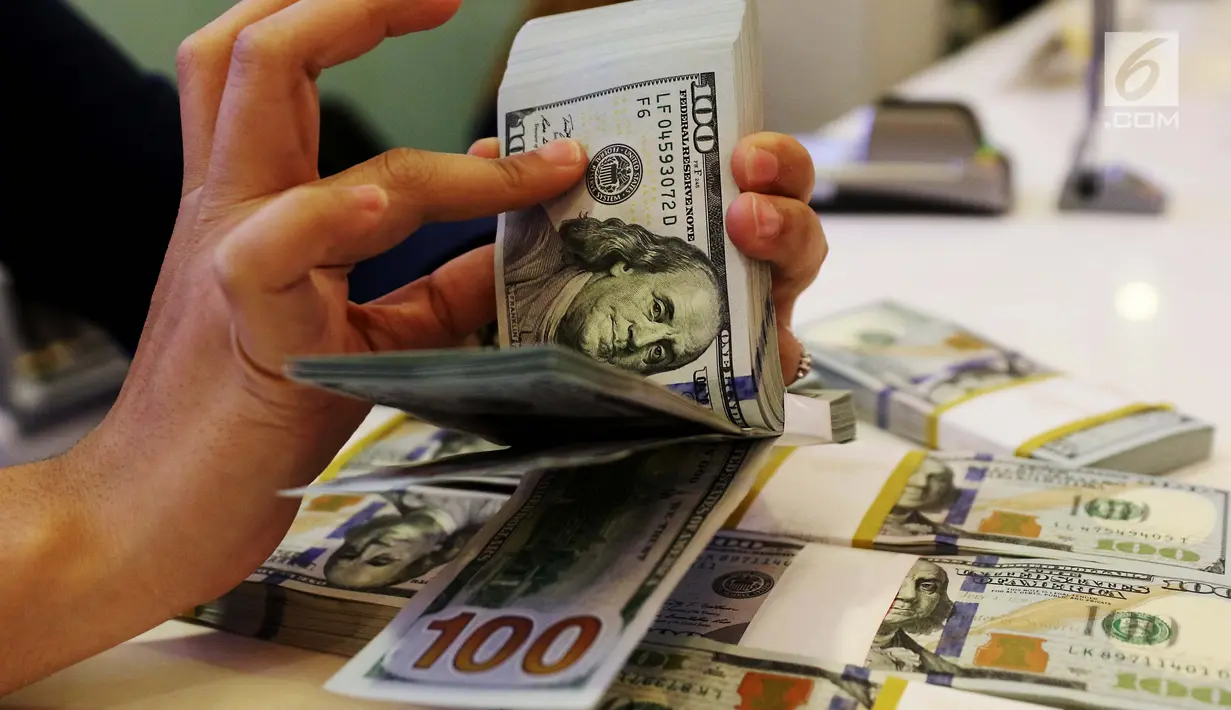 Petugas bank menghitung uang dollar AS di Jakarta, Jumat (20/10). Nilai tukar Rupiah terhadap Dolar Amerika Serikat (USD) masih belum beranjak dari level Rp 13.500-an per USD. (Liputan6.com/Angga Yuniar)