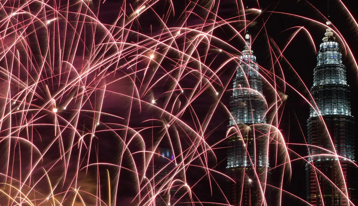 Kembang api menghiasi langit di dekat Menara Kembar Petronas Malaysia saat malam pergantian tahun di Kuala Lumpur, Malaysia. (01/1/2018). Menara Kembar Petronas menjadi salah satu spot para wisatawan menikmati malam tahun baru. (AFP Photo / Mohd Rasfan)
