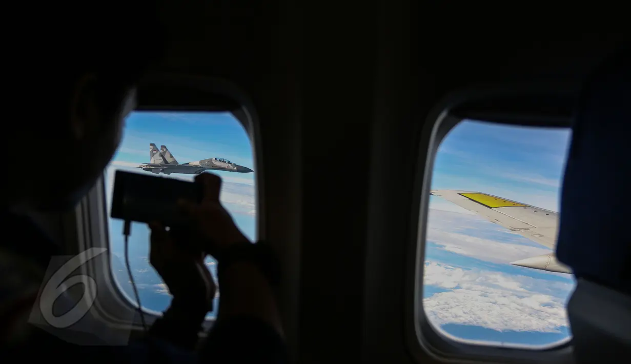 Pesawat tempur Sukhoi terlihat mengikuti rombongan pesawat yang ditumpangi Wapres Jusuf Kalla menuju Jakarta, Senin (8/6/2015). Para anggota Paspampres pun turut mengabadikan pesawat Sukhoi tersebut. (Liputan6.com/Faizal Fanani)