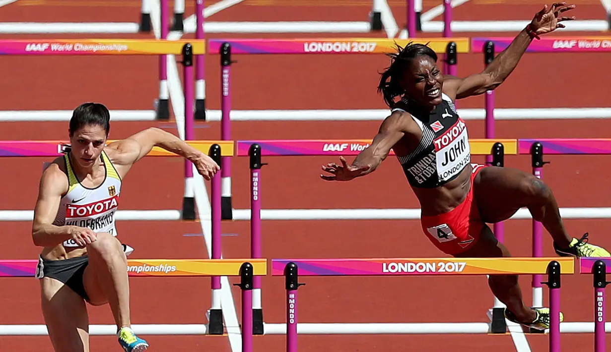 Atlet asal Trinidad dan Tobago, Deborah John (kanan) kehilangan keseimbangan saat melewati rintangan kelima dalam cabang lari halang rintang 100 meter putri Kejuaraan Atletik Dunia yang digelar di Stadion London, Inggris (11/8). (Jonathan Brady/PA via AP)