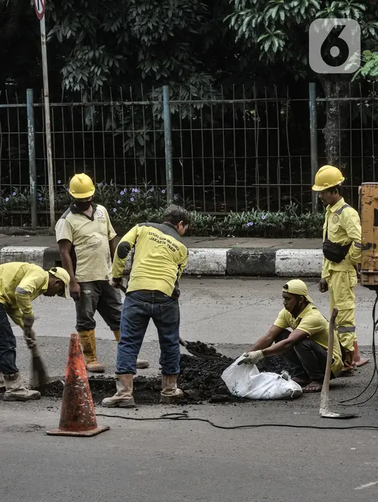 Aktivitas perbaikan jalan berlubang di Jalan DI Panjaitan, Cawang, Jakarta, Senin (25/1/2021). Perbaikan jalan rusak dan berlubang akibat sering tergenang banjir di kawasan tersebut dilakukan untuk mengantisipasi terjadinya kecelakaan pengendara. (merdeka.com/Iqbal S Nugroho)