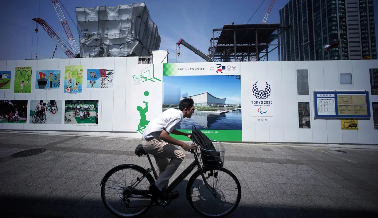 Pengendara sepeda melintasi Ariake Arena yang dalam pembangunan selama tur media ke sejumlah venue Olimpiade Tokyo 2020 di Tokyo, Selasa (17/7). Nantinya, Ariake Arena akan menjadi venue untuk cabang bola voli dan basket kursi roda. (AP/Eugene Hoshiko)