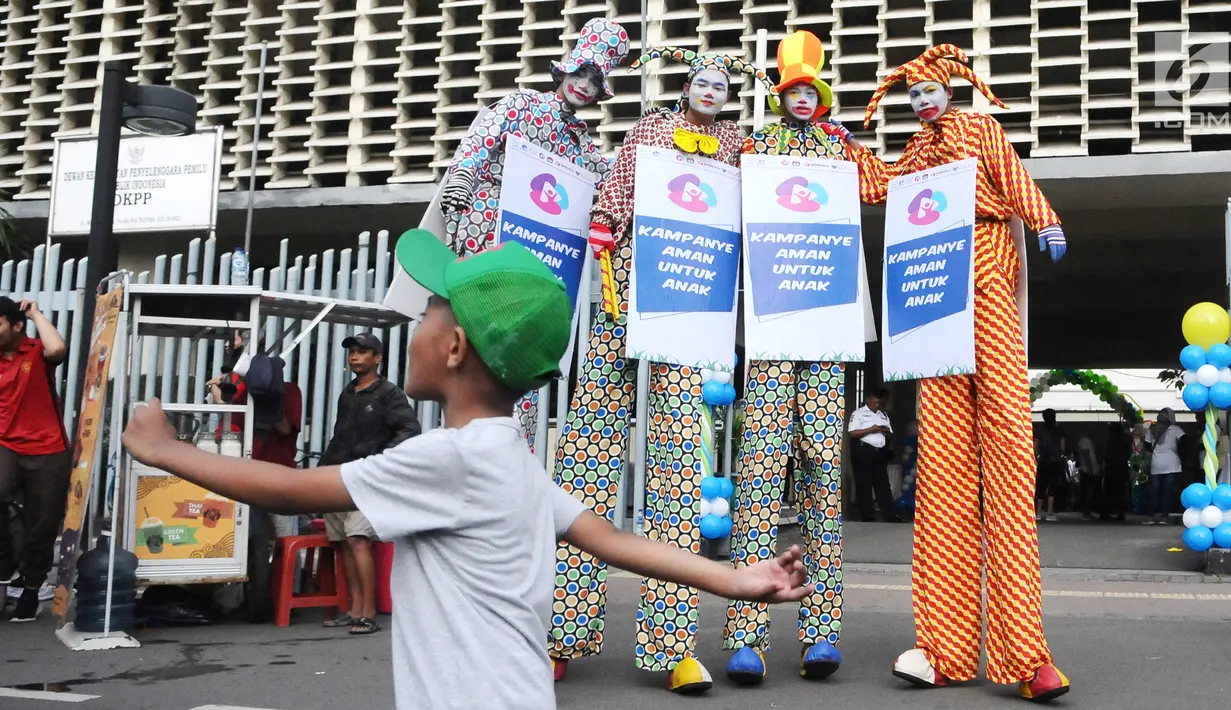 Tiga seniman egrang membawa poster Kampanye Aman Untuk Anak pada acara Deklarasi Pemilu Ramah Anak di Gedung Bawaslu, Jakarta, Minggu (17/3). KPU melarang anak-anak untuk terlibat dalam aktivitas kampanye politik. (Liputan6.com/Herman Zakharia)