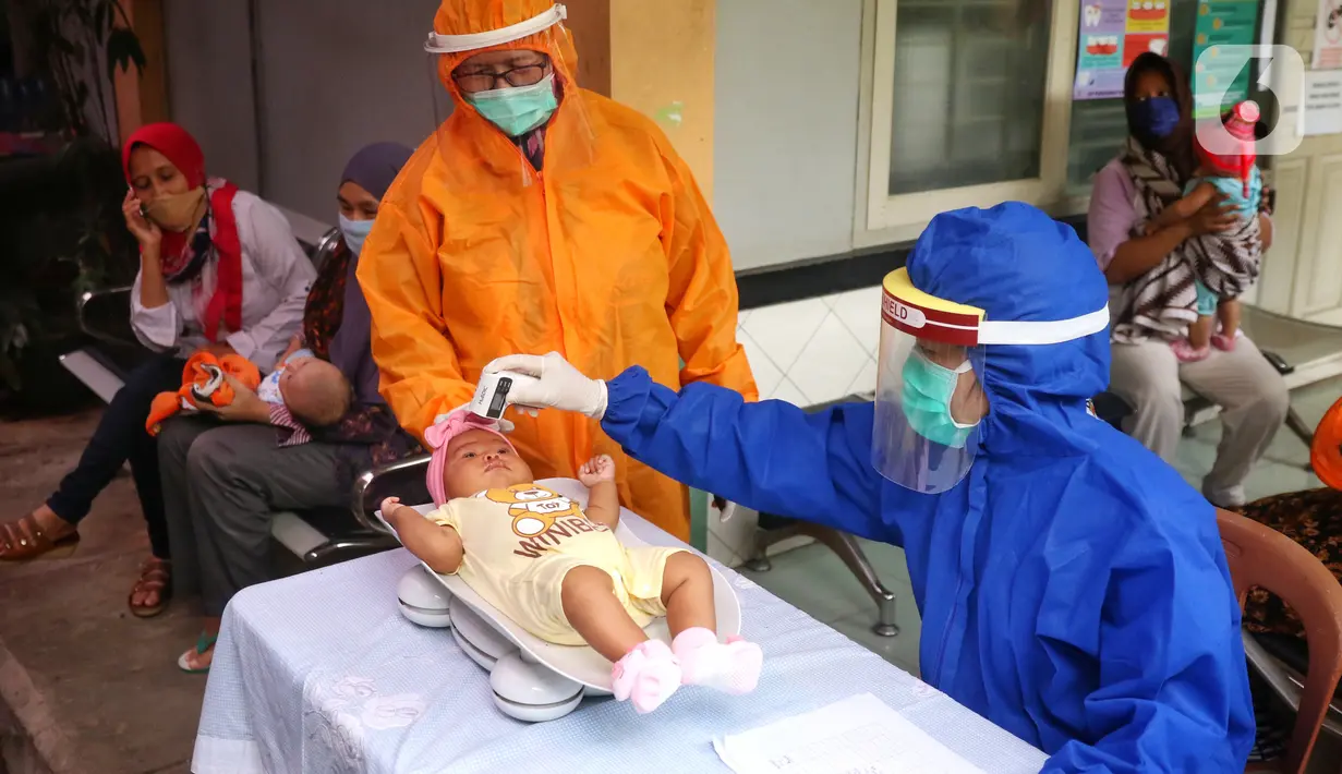 Bidan mengenakan alat pelindung diri (APD) saat melakukan imunisasi kepada bayi di Puskesmas Karawaci Baru, Tangerang, Banten, Rabu (13/5/2020). Pelayanan imunisai sesuai jadwal ini diberikan kepada bayi untuk menambah kekebalan imun tubuh. (Liputan6.com/Angga Yuniar)