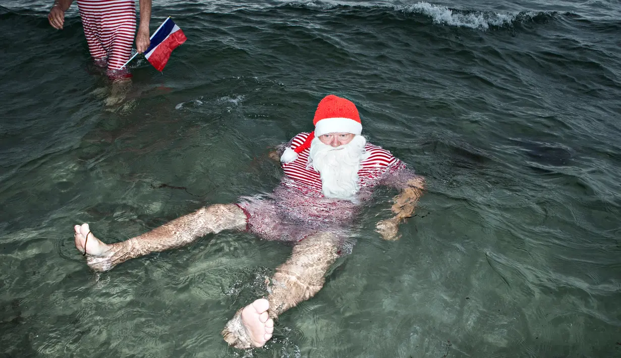 Seorang sinterklas berendam di air laut Klampenborg di luar Kopenhagen, Denmark, Selasa (25/7). Lima bulan menjelang natal, ratusan Sinterklas berkumpul dalam Kongres Dunia Sinterklas yang ke 60. (Tobias Nicolai / Ritzau Foto via AP)