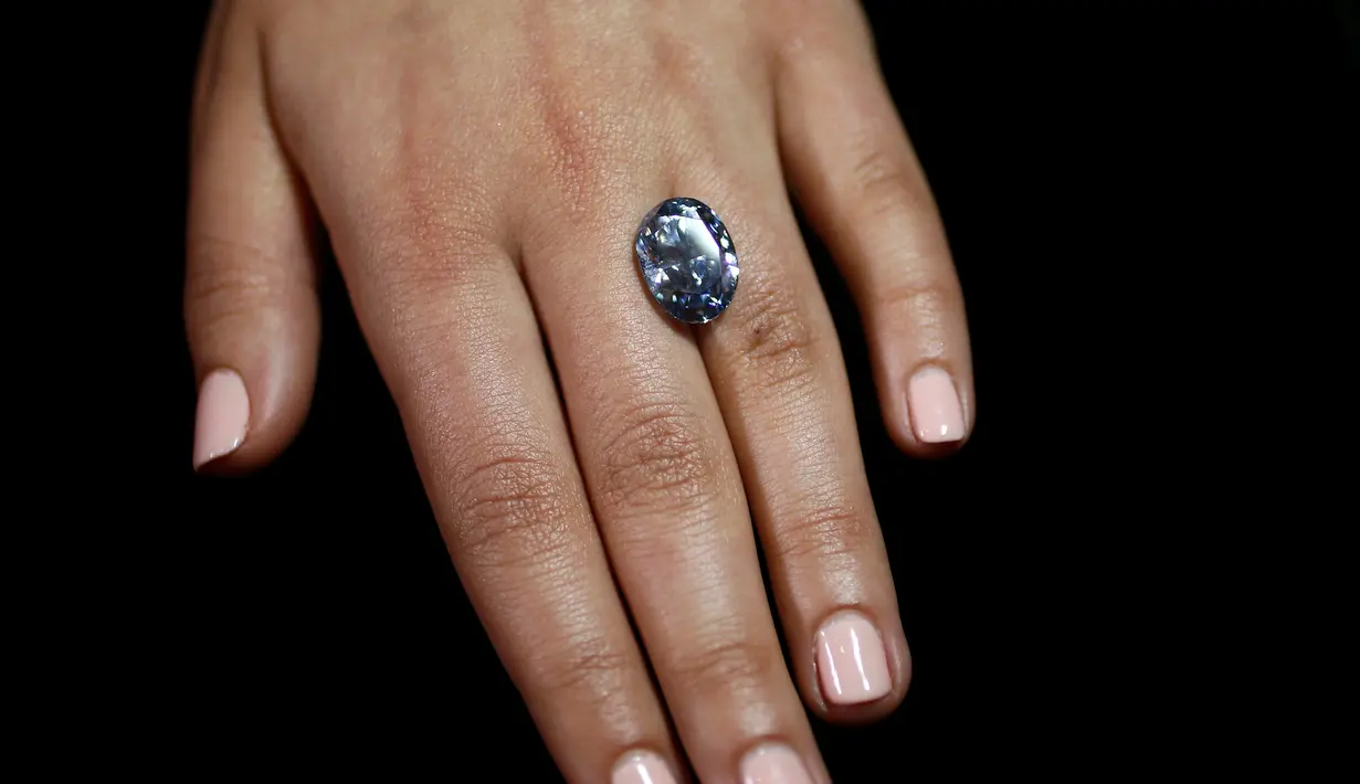 Seorang petugas sedang melihat berlian biru 10,10 karat di rumah lelang sothbey, London, Inggris, Selasa (15/3). Berlian berbentuk oval ini akan dilelang di Magnificent Jewels dan Jadeite Hongkong pada 5 April 2016. (REUTERS / Stefan Wermuth)