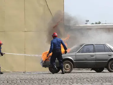 Personel menyelamatkan kebakaran sebuah mobil saat demostrasi kemampuan dalam acara Upacara Perayaan Ulang Tahun Pemadam Kebakaran (Damkar) ke-98 di Lapangan Silang Monas Selatan, Jakarta Pusat, Rabu (1/3). (Liputan6.com/Immanuel Antonius)