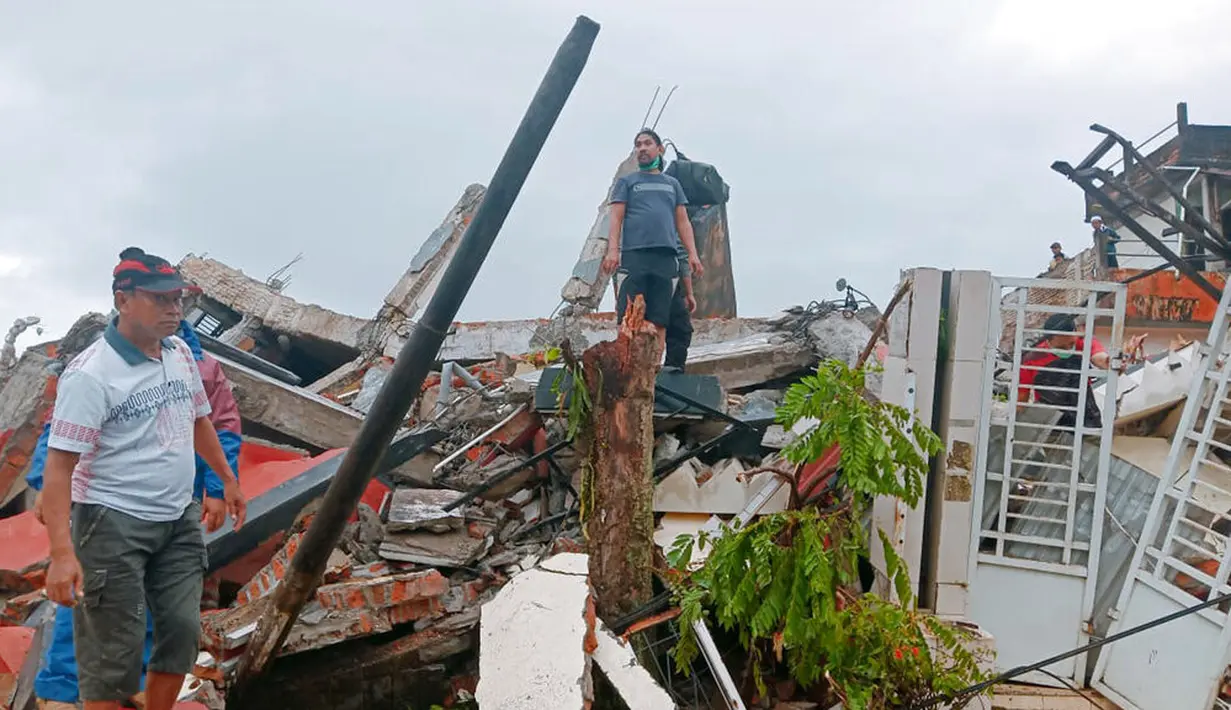 Warga memeriksa rumah-rumah yang rusak akibat gempa di Mamuju, Sulawesi Barat, Indonesia, Jumat (15/1/2021). Gempa yang berpusat di timur laut Majene tersebut terjadi pada Jumat (15/1/2021) pukul 02.28 Wita. (AP Photo/Rudy Akdyaksyah)