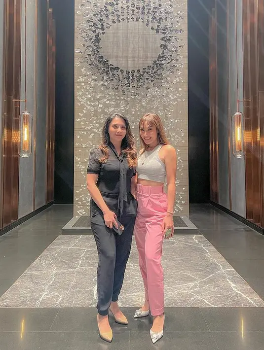 Ayu Dewi tampil kasual sembari pamer perut rata saat bertemu sahabat. Ia tampil sederhana dengan memadukan halter crop top berwarna abu-abu dengan belted pants berwarna pink. Penampilan kasualnya ini ditutup dengan heels berwarna silver dari Manolo Blahnik. (instagram/ayudewi7984)