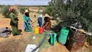 Di depan sebuah masjid kecil di Tunisia tengah, para wanita mengantre di salah satu sumber air terakhir di desa mereka, sebuah pipa yang dimaksudkan untuk irigasi tanaman, namun kini menjadi sumber kehidupan di daerah yang kering. (FETHI BELAID / AFP)