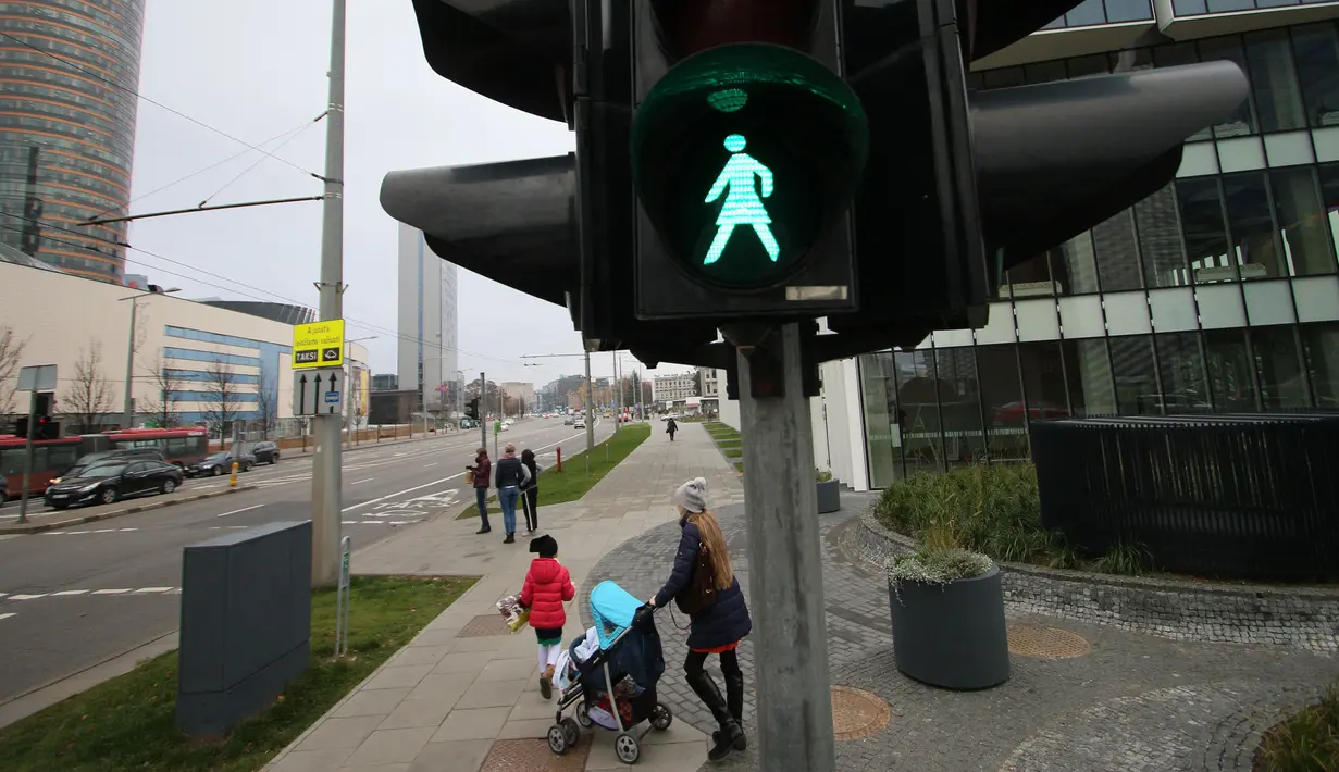 Pejalan kaki melintas dekat lampu lalu lintas bergambar wanita di Vilnius, Lituania, Jumat (2/11). Hal itu untuk merayakan ulang tahun ke-100 wanita memperoleh pengakuan internasional dalam pemungutan suara di negara baltik. (Petras Malukas/AFP)