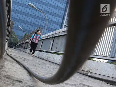 Pejalan kaki melintasi jembatan penyeberangan orang tanpa atap dan tidak terawat di Jalan TB Simatupang, Jakarta, Rabu (10/10). Kondisi tersebut menyebabkan JPO terkesan kumuh serta mengurangi kenyamanan pejalan kaki. (Liputan6.com/Immanuel Antonius)