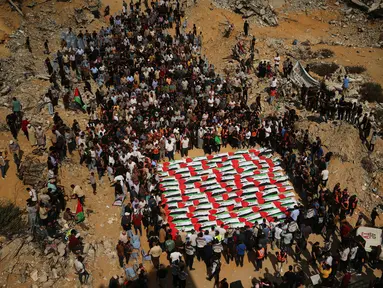 Warga Palestina berkumpul di sekitar jenazah warga Palestina yang tewas dalam serangan Israel selama perang dengan Hamas setelah ditemukan dari bawah reruntuhan bangunan, dalam prosesi pemakaman di Kota Gaza, Kamis (1/10/2026). Jenazah yang ditutupi bendera Palestina tersebut diiringi keluarga dan warga dalam suasana duka. (AP Photo/Yousef Al Zanoun)