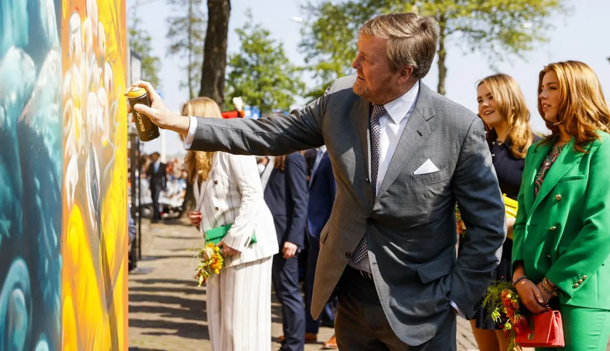 <p>Raja Belanda Willem-Alexander (kiri) menyemprotkan cat pada mural yang diapit oleh Putri Ariane (kedua dari kanan) dan Putri Alexia (kanan) saat perayaan Hari Raja di Maastricht, Belanda, Rabu (27/4/2022). Setelah dua tahun hening karena pandemi COVID-19, Belanda kembali merayakan Hari Raja seperti biasa. (Remko de Waal/ANP/AFP)</p>