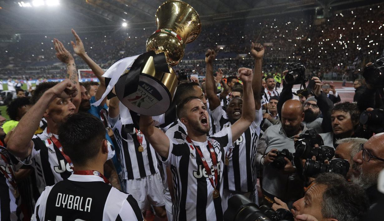 Pemain Juventus, Miralem Pjanic mengangkat trofi juara Coppa Italia usai mengalahakan AC Milan pada laga final di Rome Olympic stadium, (9/5/2018). Juventus menang 4-0. (AP/Gregorio Borgia)