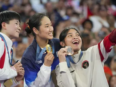 Pebulu tangkis tunggal putri Indonesia, Gregoria Mariska Tunjung sukses menyumbang medali pertama bagi kontingen Indonesia di Olimpiade Paris 2024. Medali perunggu yang didapatnya tanpa harus bertanding menghadapi Carolina Marin yang mundur akibat cedera di semifinal, dirayakan Jorji di atas podium juara dengan berswafoto dengan peraih medali emas, An Se-young dan peraih medali perak, He Bing Jiao saat upacara penyerahan medali di Porte de La Chapelle Arena, Paris, Senin (5/8/2024). (AP Photo/Kin Cheung)