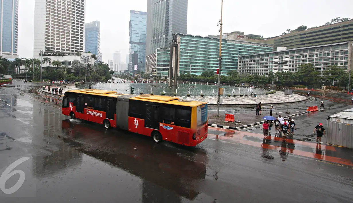 Bus Transjakarta melintas di kawasan Car Free Day, Jakarta, Minggu (28/2/2016). Hujan yang mengguyur Ibukota sejak semalam hingga pagi membuat kawasan CFD sepi pengunjung. (Liputan6.com/Immanuel Antonius)