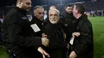 Presiden PAOK Ivan Savvidis diamankan petugas setelah turun ke lapangan dengan pistol di pinggangnya saat Liga Super Yunani di Stadion Toumbas, Minggu (11/3). Laga yang mempertemukan PAOK dengan AEK Athens terpaksa harus ditunda. (SAKIS MITROLIDIS/AFP)
