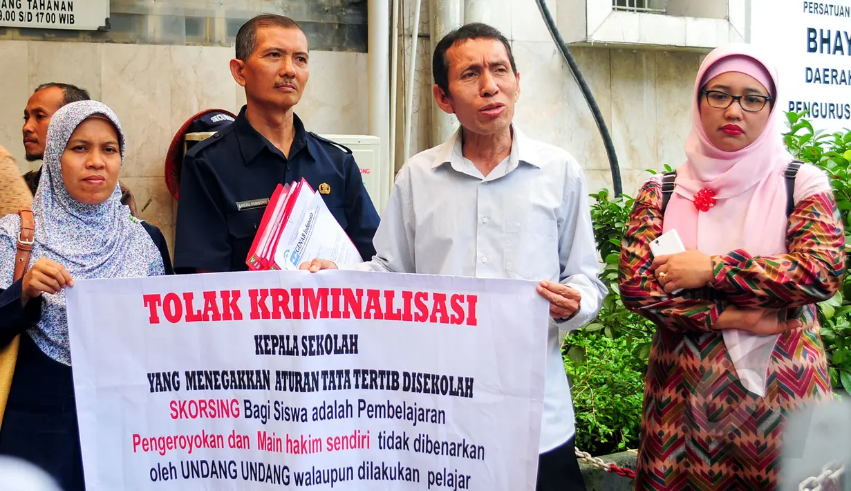 Retno Listyarti (kanan) di temani sejumlah guru membawa spanduk yang mendukungnya di Polda Metro Jaya, Jakarta, Selasa (10/3/2015). Retno Listyarti diperiksa terkait laporan orangtua murid SMAN 3 Jakarta. (Liputan6.com/Yoppy Renato)  