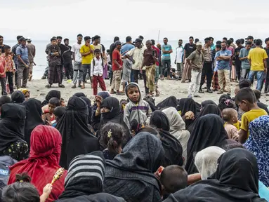 Pengungsi Rohingya duduk bersama di tanah setelah mereka tiba dengan perahu di Pantai Kalee, Laweung, Kabupaten Pidie, Provinsi Aceh, Indonesia, Selasa (14/11/2023). Hampir 200 pengungsi Rohingya, termasuk banyak perempuan dan anak-anak, terdampar di provinsi paling barat Indonesia pada 14 November, menurut laporan setempat. (Jon S./AFP)