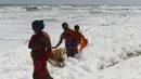 Penduduk setempat berjalan di atas limbah busa yang disebabkan polutan saat bercampur dengan ombak di pantai di Chennai (29/11/2019). Limbah busa tersebut  membuat penduduk dan pengunjung pantai merasa sakit. (AFP/Arun Sankar)