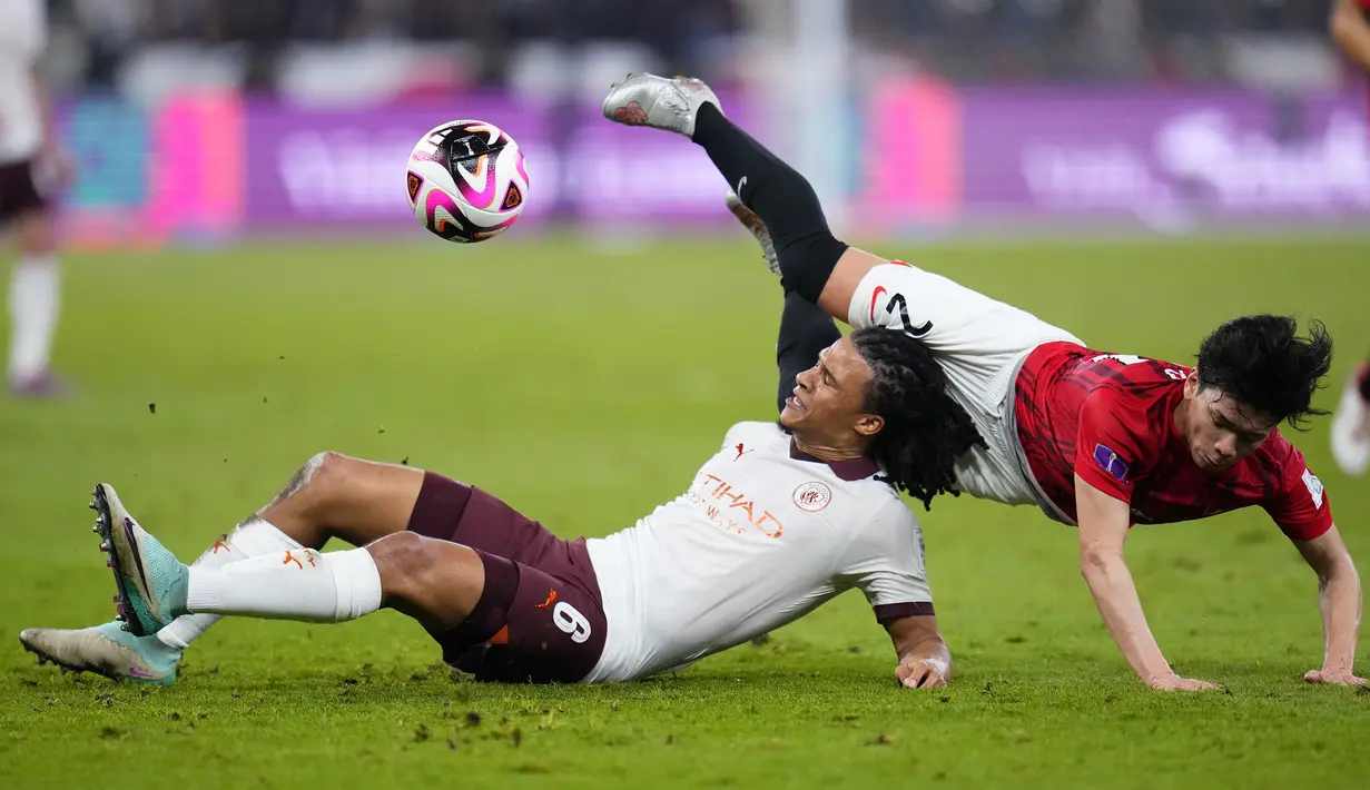 Bek Manchester City, Nathan Ake (kiri) dan gelandang Urawa Red Diamonds, Tomoaki Okubo terjatuh saat perebutan bola pada laga semifinal Piala Dunia Klub 2023 di King Abdullah Sports City Stadium, Jeddah, Arab Saudi, Rabu (20/12/2023) dini hari WIB. (AP Photo/Manu Fernandez)
