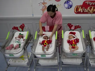 Perawat merapikan pakaian bayi yang baru lahir di Rumah Sakit Synphaet, Bangkok, Thailand, Selasa (24/12/2019). Bayi-bayi tersebut dipakaikan kostum sinterklas untuk menyambut Hari Raya Natal. (AP Photo/Sakchai Lalit)