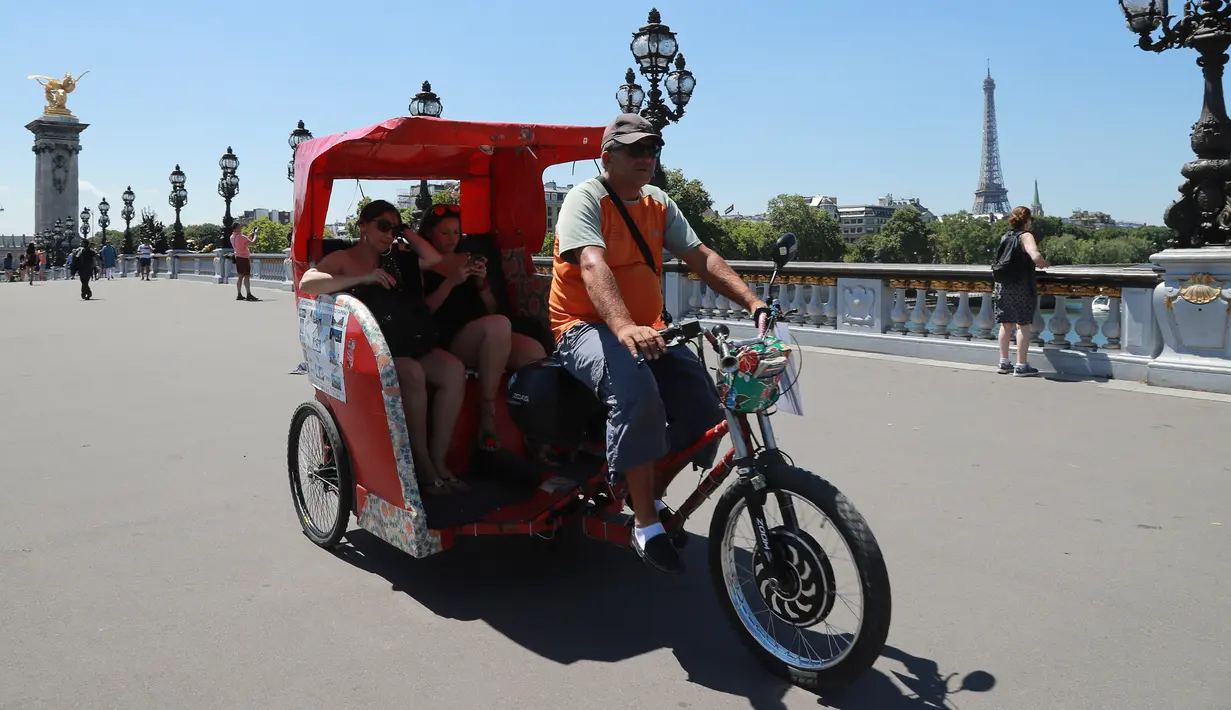 Wisatawan berkeliling kota Paris menggunakan transportasi becak, Prancis, (7/7). Desain becak di Paris ini memiliki posisi penarik becak dibagian depan berbeda dengan becak yang ada di Indonesia. (AFP Photo/Jacques Demarthon)