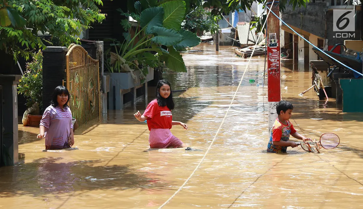 Anak-anak melintasi banjir yang menggenangi kawasan Pejaten Timur, Jakarta, Jumat (26/4). Banjir yang berasal dari luapan Sungai Ciliwung tersebut merendam ratusan rumah warga hingga kedalaman lebih dari satu meter. (Liputan6.com/Immanuel Antonius)