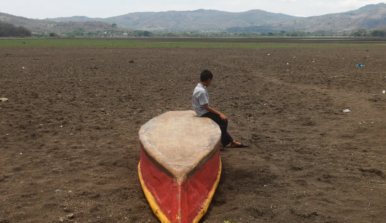 Seorang anak laki-laki duduk di atas kapal di Danau Atescatempa yang telah mengering, Guatemala, Jumat (5/5). Keringnya Danau Atescatempa disebabkan oleh dampak perubahan iklim di Amerika Tengah yang disebut "Koridor Kering". (AFP PHOTO / Marvin RECINOS)