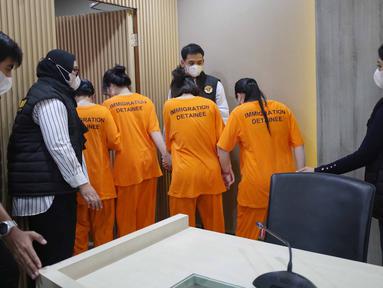 Petugas menggiring Warga Negara Asing (WNA) asal Vietnam yang tertangkap usai rilis penangkapan pelanggar izin tinggal di kantor Direktorat Jenderal (Ditjen) Imigrasi, Jakarta, Jumat (10/1/2025). (Liputan6.com/Angga Yuniar)