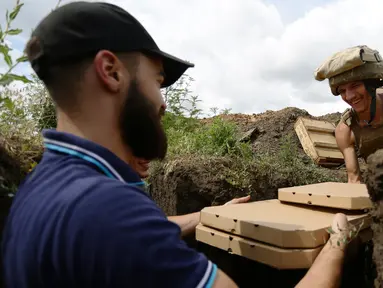 Aleksey Kachko, salah satu pemilik kedai Pizza Veterano di Mariupol menyerahkan sekotak pizza kepada seorang tentara Ukraina yang bertugas di garis depan menghadapi separatis pro-Rusia di wilayah timur negeri itu, 19 Juli 2018. (AFP/Aleksey FILIPPOV)
