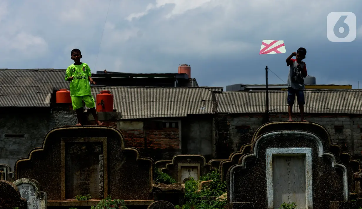Anak-anak menerbangkan layang-layang di Tanah Makam Cipinang Besar Utara, Jakarta, Selasa (14/1/2020). Pemprov DKI Jakarta berencana terus menambah Ruang Publik Terpadu Ramah Anak (RPTRA) di sejumlah wilayah. (merdeka.com/Imam Buhori)