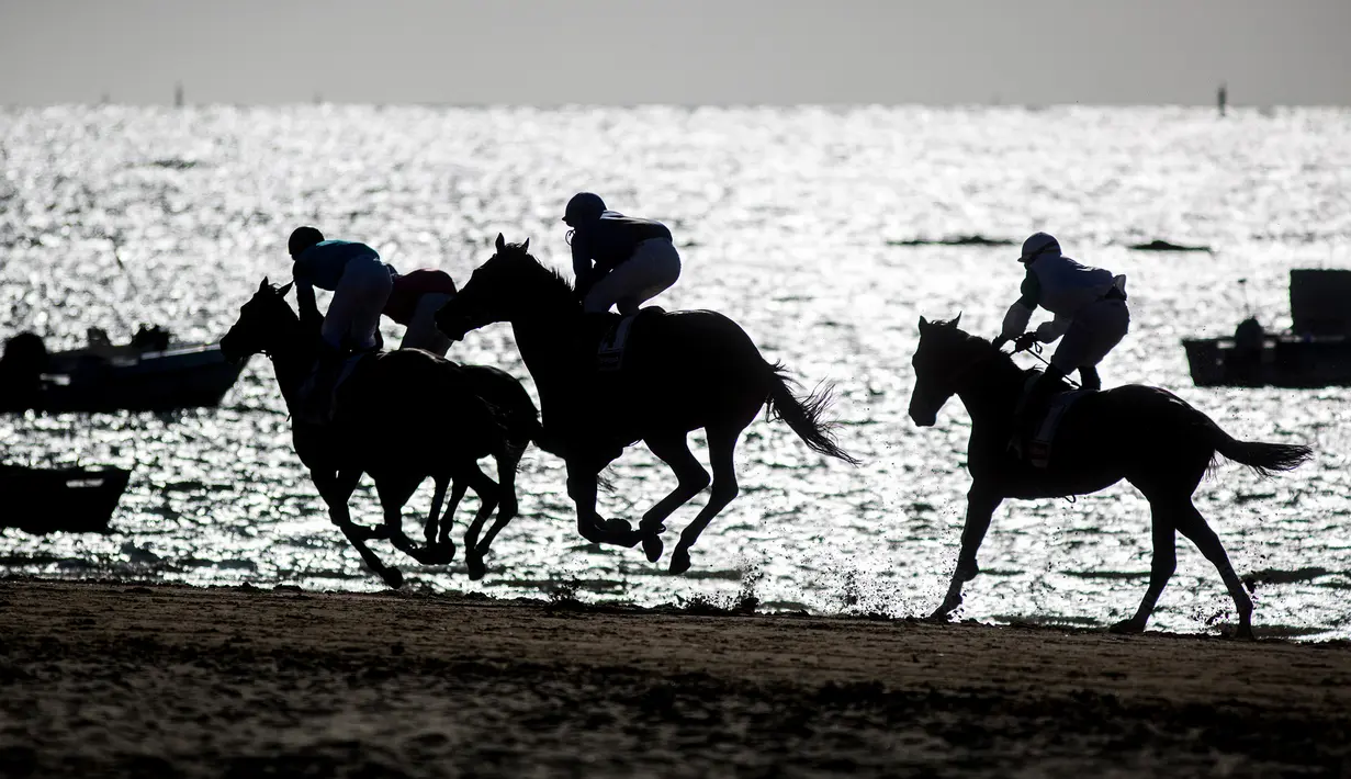 Sejumlah joki memacu kuda mereka pada lomba pacuan kuda di sepanjang pantai di Sanlucar de Barrameda, Spanyol pada 11 Agustus 2019. Balap kuda di tepi pantai ini merupakan acara tahunan yang telag berlangsung selama lebih dari 140 tahun. (AP Photo/Javier Fergo)