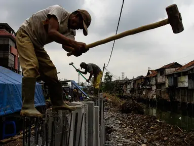 Pekerja menggarap pemasangan turap di kawasan Kali Roxy, Jakarta, Senin (14/11). Pemasangan dinding turap tersebut guna mengantisipasi luapan air kali saat musim penghujan. (Liputan6.com/Faizal Fanani)