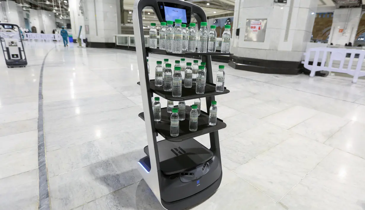 Sebuah gambar pada 15 Juni 2021 menunjukkan robot pembawa air Zamzam yang digunakan pertama kalinya di sekitar Masjidil Haram di Makkah, Arab Saudi. Robot itu masing-masing dilengkapi tiga rak berisi air zamzam botolan sehingga para jemaah bisa mengambil sendiri tanpa kontak langsung. (AFP Photo)