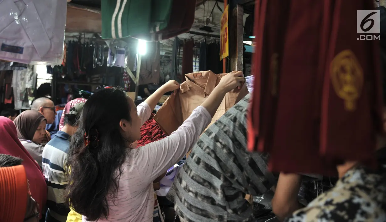 Orangtua memilih seragam sekolah di Pasar Jatinegara, Jakarta, Minggu (14/7/2019). Jelang tahun ajaran baru, Pasar Jatinegara ramai didatangi para orangtua yang mencari seragam sekolah untuk anaknya. (merdeka.com/Iqbal Nugroho)