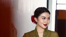 Penampilan memukau Ariel Tatum pakai kebaya hijau dan kain batik cokelat muda. Ia tata rambutnya dengan sanggul rendah, yang diberi aksesori bunga merah dan pulasan lipstik merah yang serasi. [Foto: Instagram/arieltatum]
