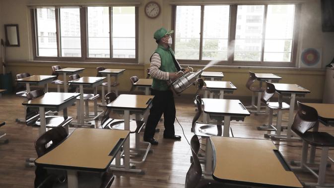 Pekerja mengenakan masker saat mendisinfeksi kelas di Sekolah Menengah Putri Yeouido, Seoul, Korea Selatan, Selasa (19/5/2020). Sekolah-sekolah di Korea Selatan secara bertahap akan mulai dibuka pada 20 Mei 2020. (AP Photo/Ahn Young-joon)