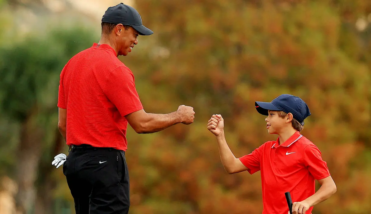 Maestro golf Tiger Woods tampak begitu dekat dengan anaknya yang bernama Charlie Axel Woods. (Mike Ehrmann/Getty Images/AFP)