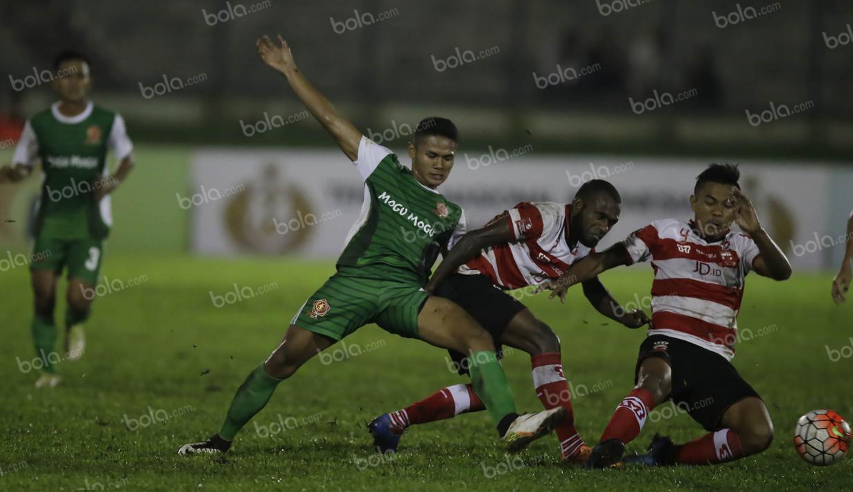 Pemain PS TNI, Dimas Drajad, berebut bola dengan pemain Madura United, Engelberd Sani dan Asep Berlian (kanan), dalam laga Torabika Soccer Championship presented by IM3 Ooredoo di Stadion Siliwangi, Bandung, Minggu (1/5/2016). (Bola.com/Vitalis Yogi Trisn