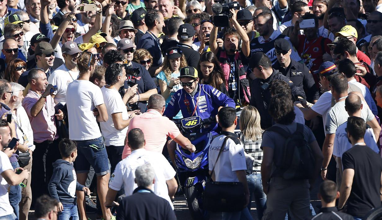 Valentino Rossi berusaha menembus kerumunan penggemarnya saat akan kembali ke paddock di Sirkuit Ricardo Tomo, Valencia, Spanyol, (7/11/2015). (EPA/Kai Foersterling)