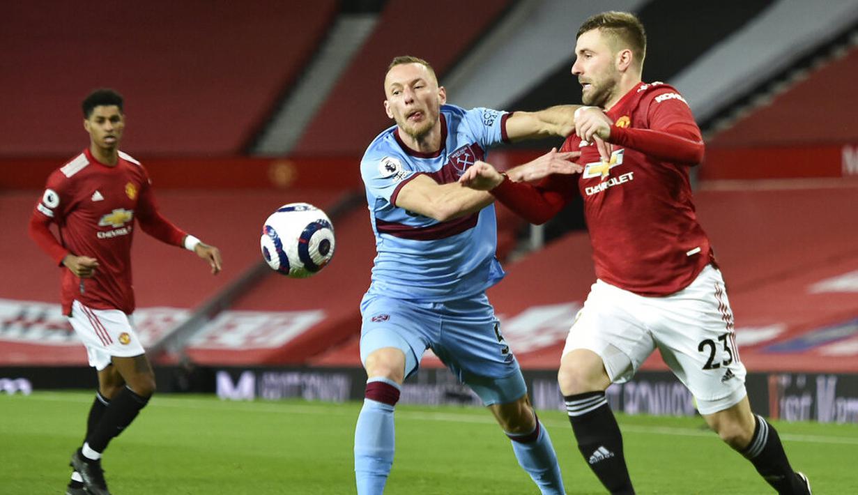 Bek Manchester United, Luke Shaw, berebut bola dengan pemain West Ham United, Vladimir Coufal, pada laga Liga Inggris di Stadion Old Trafford, Minggu (15/3/2021). Setan Merah menang dengan skor 1-0. (AP/Clive Brunskill,Pool)