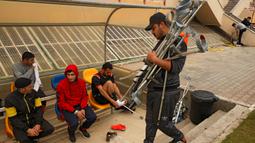 Seorang ofisial tim menyiapkan kruk menjelang pertandingan final kejuaraan lokal sepak bola korban amputasi antara Al-Jazeera melawan Al-Abtal yang diselenggarakan oleh Komite Palang Merah Internasional (ICRC), di tengah pandemi COVID-19, di Kota Gaza, (18/3/2021). (AFP/Mohammed Abed)